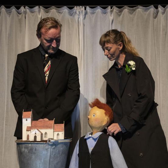 billede af en mand, en kvinde og en dukke der kigger på en model af en kirke