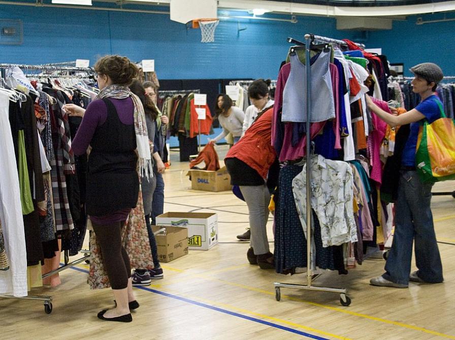 Billede af fyldte tøjstativer og mennesker der ser på tøjet